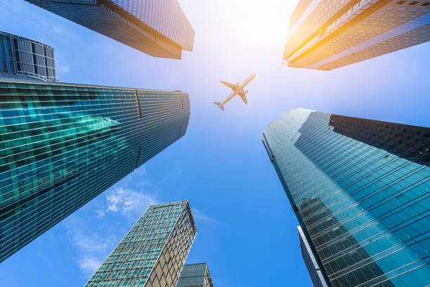 Low angle view of airplane flying over skyscrapers stock photo