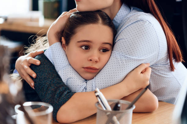 Young sad mother hugs little upset daughter sitting in lawyer's office for divorce. stock photo