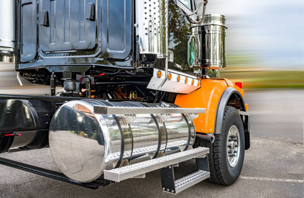 Shiny big rig semi truck tractor in black and orange with polisher aluminum fuel tanks and steps and another accessories ready to go for freight Powerful shiny big rig semi truck tractor in black and orange with polisher aluminum fuel tanks and steps and another accessories ready to go for industrial heavy freight car transporter stock pictures, royalty-free photos & images