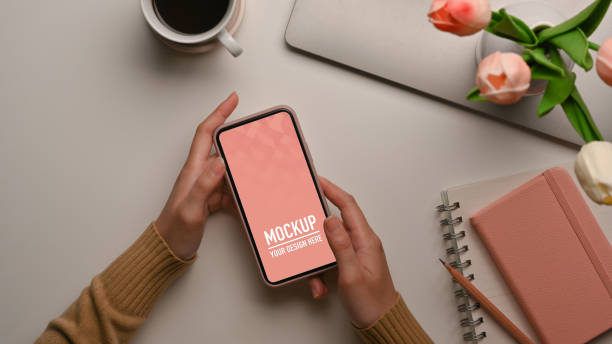 istock Female hands holding smartphone on feminine workspace 1286297827