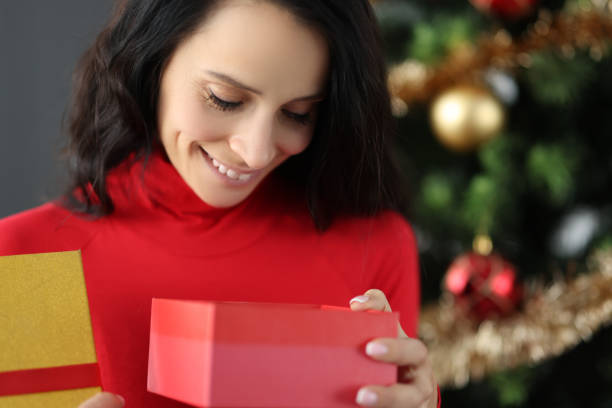 istock Young smiling woman looking into box with gift for new year 1286301839