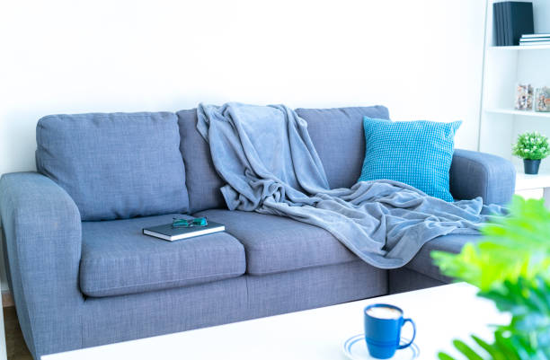 istock Modern gray couch with blanket and pillow. Copy space on the wall 1286303837