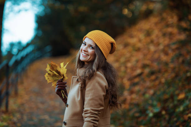 istock smiling young female in brown coat and yellow hat 1286304328
