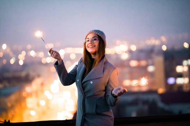 istock Smiling girl on rooftop holding burning sparkler. 1286308477
