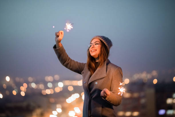 Girl holding burning sparklers on the rooftop stock photo