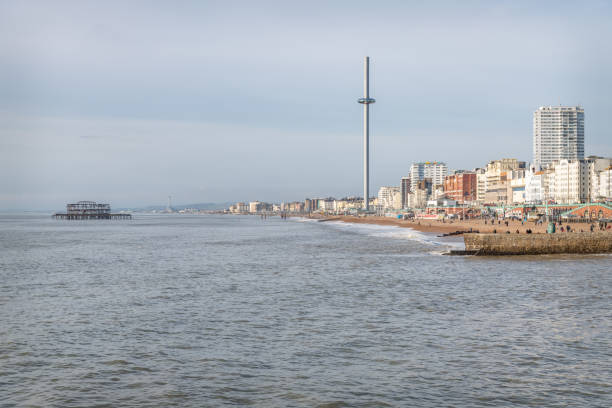 Aerial view of Regency and Victorian architecture of the coastal resort town of Brighton, UK. We can see the piers of Brighton and people walking along the sandy beach and seafront. Houses and traditional victorian architecture recede into the background. Horizontal colour image with copy space.