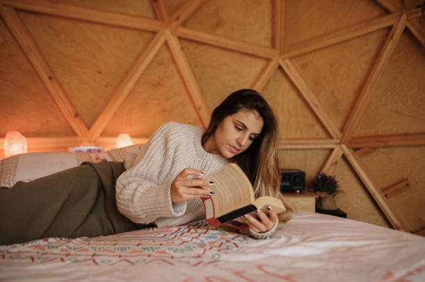 istock Young woman reading and lying on bed 1286309230