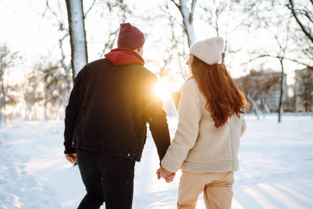 istock Young couple hugging and laughing outdoors in winter at sunset. 1286312637