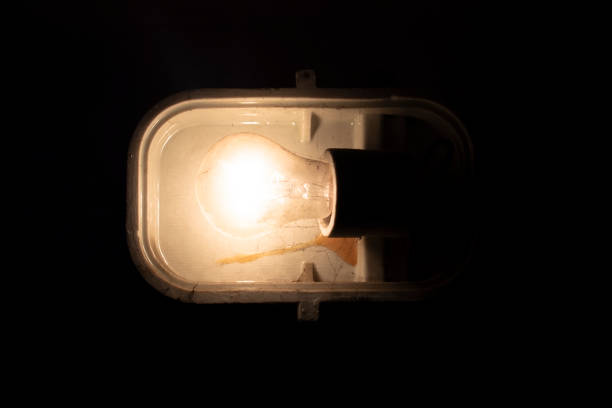 Industrial lamp in the dark room Loft industrial stylized lamp / reflector/ headlight / spotlight hanging on the dirty wall in the basement / magazine attic old light bulb loft apartment stock pictures, royalty-free photos & images