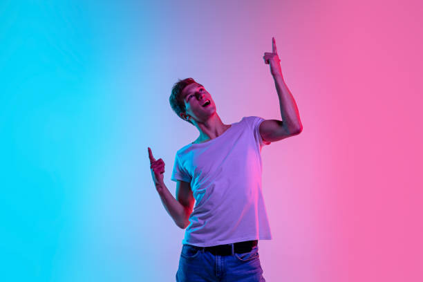 istock Young caucasian man's portrait on gradient blue-pink studio background in neon light 1286319545