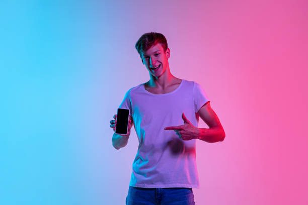 istock Young caucasian man's portrait on gradient blue-pink studio background in neon light 1286319555
