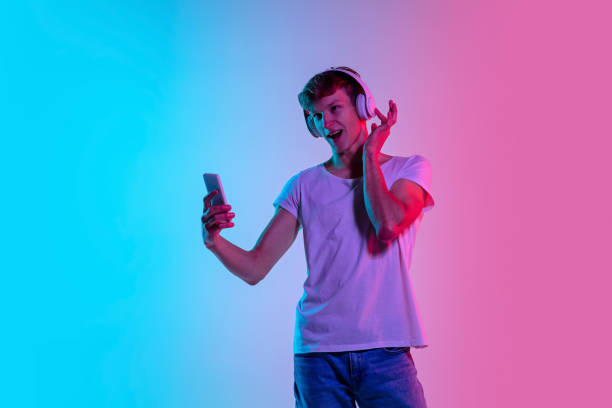 istock Young caucasian man's portrait on gradient blue-pink studio background in neon light 1286319569