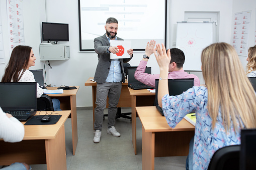 Driving instructor holding an image of a STOP traffic sign and showing it to his students in the classroom