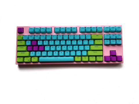 Pink keyboard with bright blue purple green key, unicorn color theme style on white background.