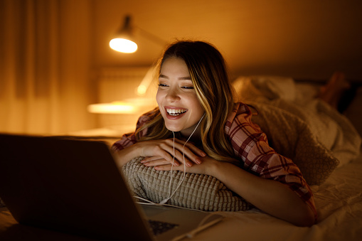 Portrait of a young woman watching a movie at night in her bedroom