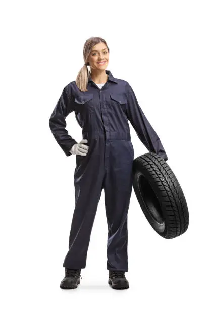 Full length portrait of a female auto mechanic holding a vehicle tire isolated on white background