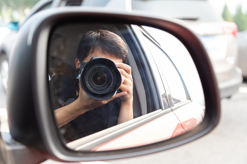 Photographer taking a selfie in the car rearview mirror