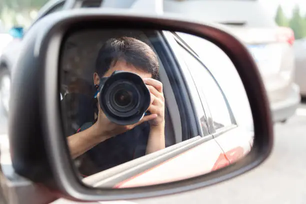 Photo of Photographer taking a selfie in the car rearview mirror