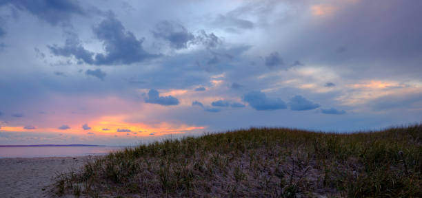 istock Sunset Seascape and Cloudscape over Grass Covered Sand Dune 1286332239