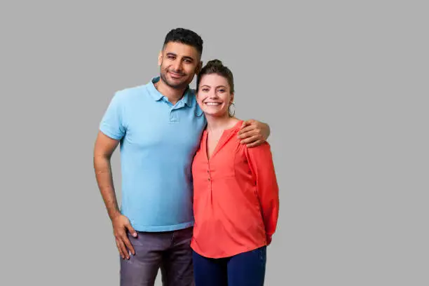 Photo of Portrait of young attractive family couple embracing. isolated on gray background, indoor studio shot