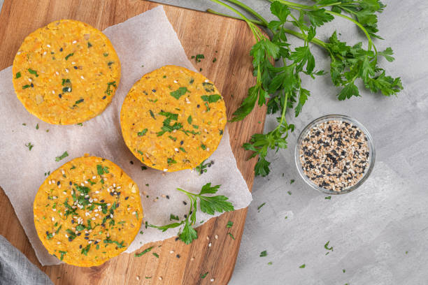 Raw veggie burger with chickpeas, vegetables and parsley leaves on kitchen countertop Raw veggie burger with chickpeas, vegetables and parsley leaves on kitchen countertop veggie burger stock pictures, royalty-free photos & images