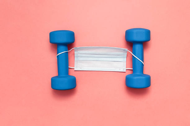 istock blue dumbbells on pink background with medical mask 1286335941