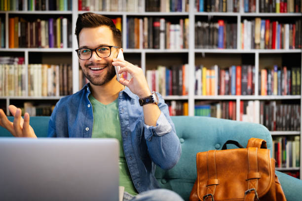 istock Cheerful smiling man talking on phone and working, studying on laptop 1286336907