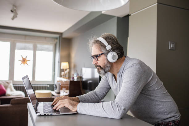 istock Senior man using a laptop at home in pajamas 1286339889