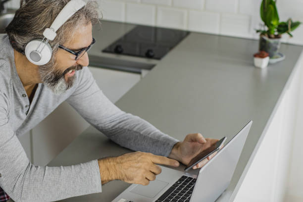 istock Senior man using a laptop at home in pajamas 1286340836