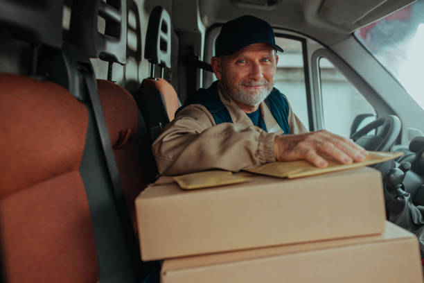 istock Smiling delivery man in his van with boxes on front seat 1286347277