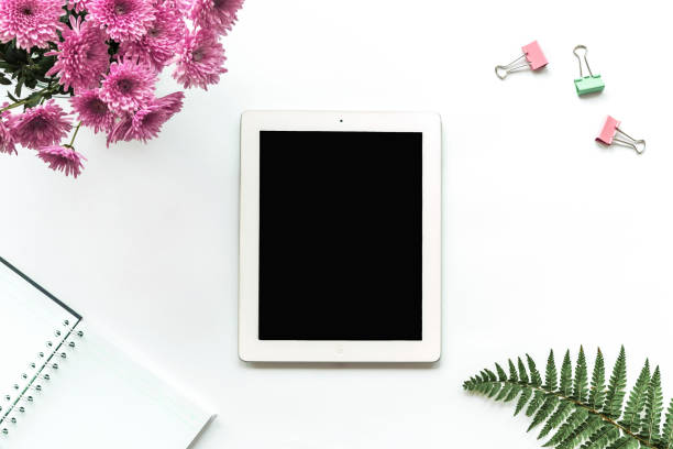istock Tablet computer, notebook, paper clips, pink chrysanthemums and fern leaves on a white background. Top view, copy space 1286347492