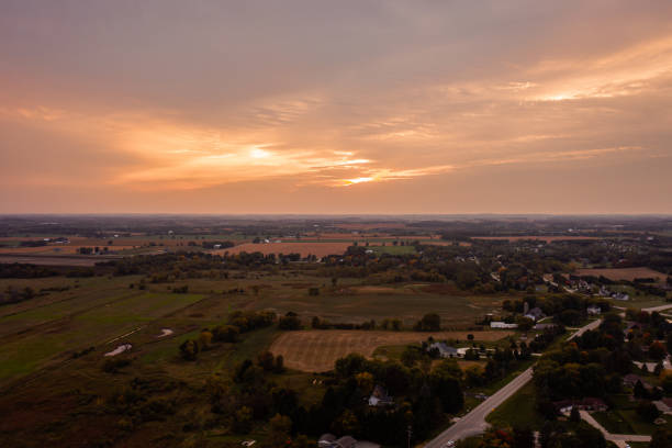 um lindo céu aéreo e uma fotografia de paisagem de uma nuvem cor de rosa e laranja sobre terras rurais e casas perto de slinger, wisconsin. - slinger - fotografias e filmes do acervo