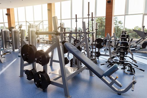 Interior of modern gym fitness room with sports and fitness equipment against the windows