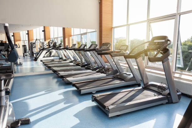 Interior of modern gym fitness room with large windows and treadmills Interior of modern gym fitness room with large windows and treadmills health club stock pictures, royalty-free photos & images