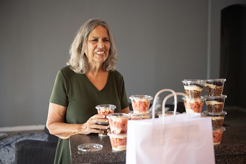 A Puerto Rican woman in her 70s smiles after receiving the gift of individual sized homemade cake desserts from a relative in Orlando, Florida.