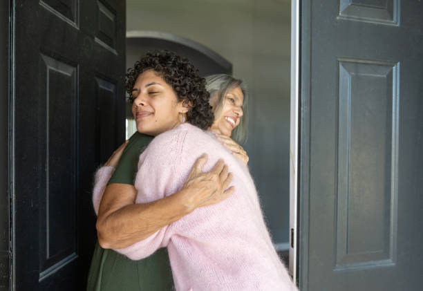 joven hispana abrazando a la abuela mayor en la puerta principal - puertorriqueño fotografías e imágenes de stock