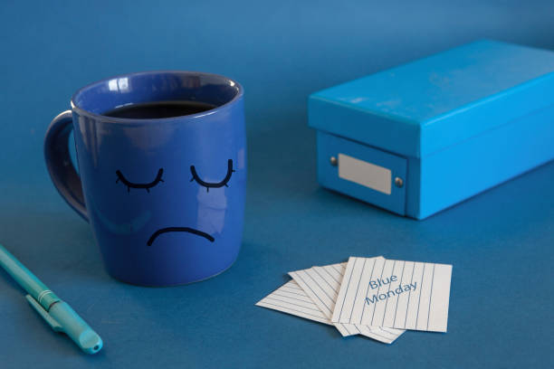 el comienzo de la jornada laboral del lunes azul. taza de té, despertador y una nota con el texto blue monday. el día más deprimido del año - musgo apretado fotografías e imágenes de stock