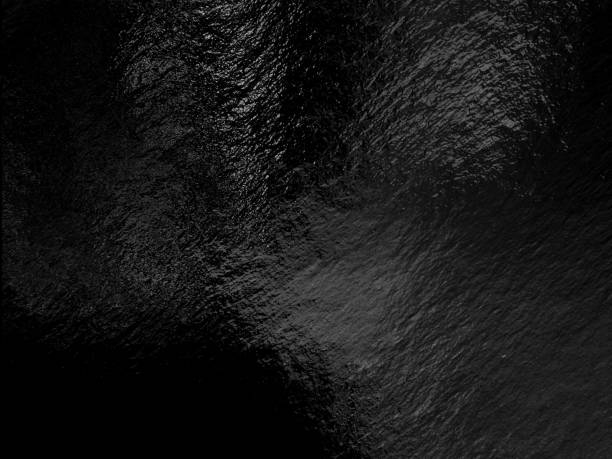 istock Black foil background with highlights and uneven texture 1286358041