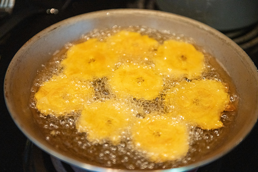 Sliced and smashed green plantains are fried in cooking oil to make tostones, a Puerto Rican food.