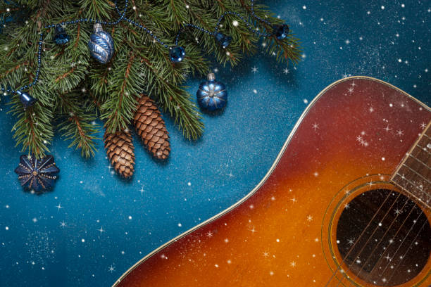アコースティックギターとクリスマスツリーの枝と青い装飾ボールが青い背景にキラキラ - ragtime ストックフォトと画像