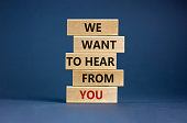Wooden blocks with words 'we want to hear from you'. Beautiful grey background. Copy space. Business concept.