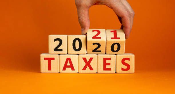 2021年規劃業務理念。男性手翻轉木塊，將銘文"2020年稅"修改為"2021年稅"。美麗的橙色背景，複製空間。 - 稅 圖片 個照片及圖片檔