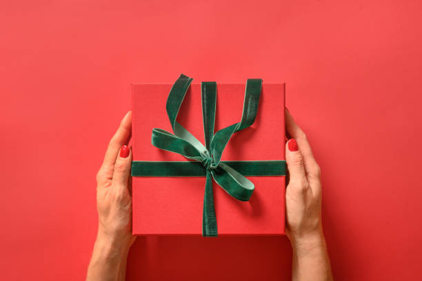 istock Christmas gift box and decorative green rope ribbon on red. 1286362503