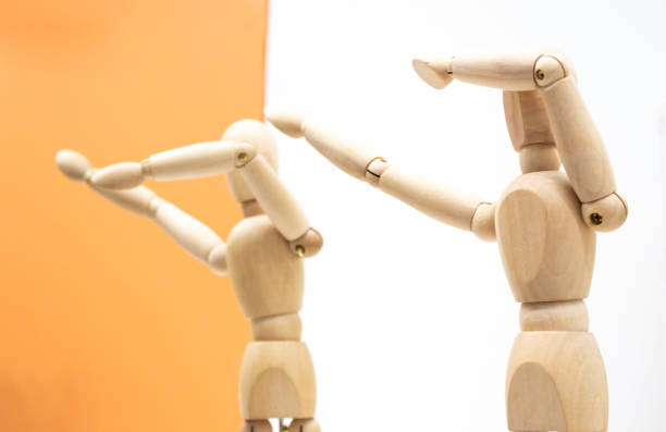 istock Two wooden human figures on white and orange backgrounds dance and make a dab movement sneezing gesture 1286362583