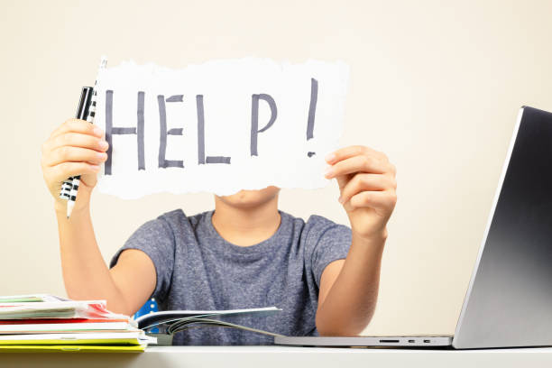 istock Learning difficulties, school, education, online remote learning concept. Sad kid sitting at table with laptop computer and holding card with Help word. 1286366601
