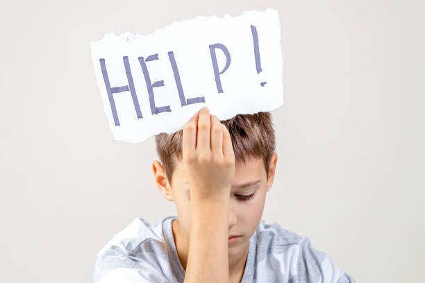 istock Sad tired frustrated boy holding torn paper card with word Help. Learning difficulties, kid emotions 1286366815