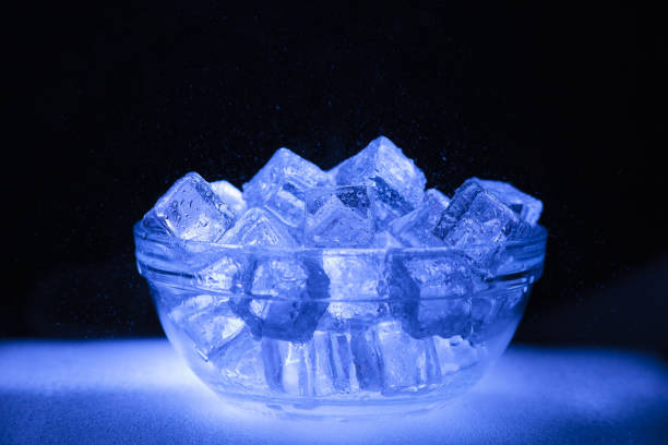 Bowl of wet ice with dark background and sprayed water droplets