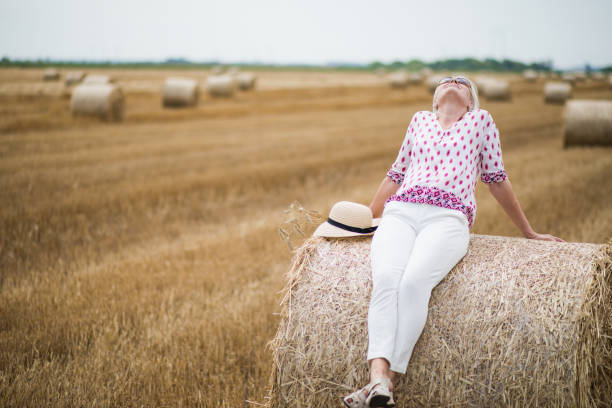 feliz atractiva mujer mayor en un campo en verano - menopausia fotos fotografías e imágenes de stock
