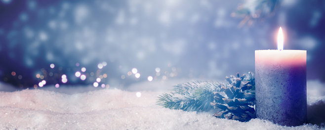 christmas decoration idyll in deep snow on blurred blue background, beautiful natural christmas background with shiny candlelight and advertising space