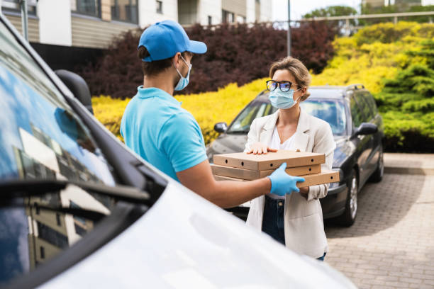 istock Safe delivery - courier on a van brings a pizza to the client 1286375935